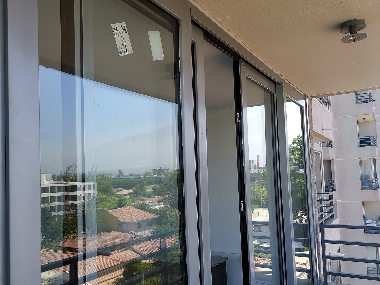 Ventanal corredero de PVC de piso a cielo, con perfiles gris claro, que da a la terraza de un departamento en altura.