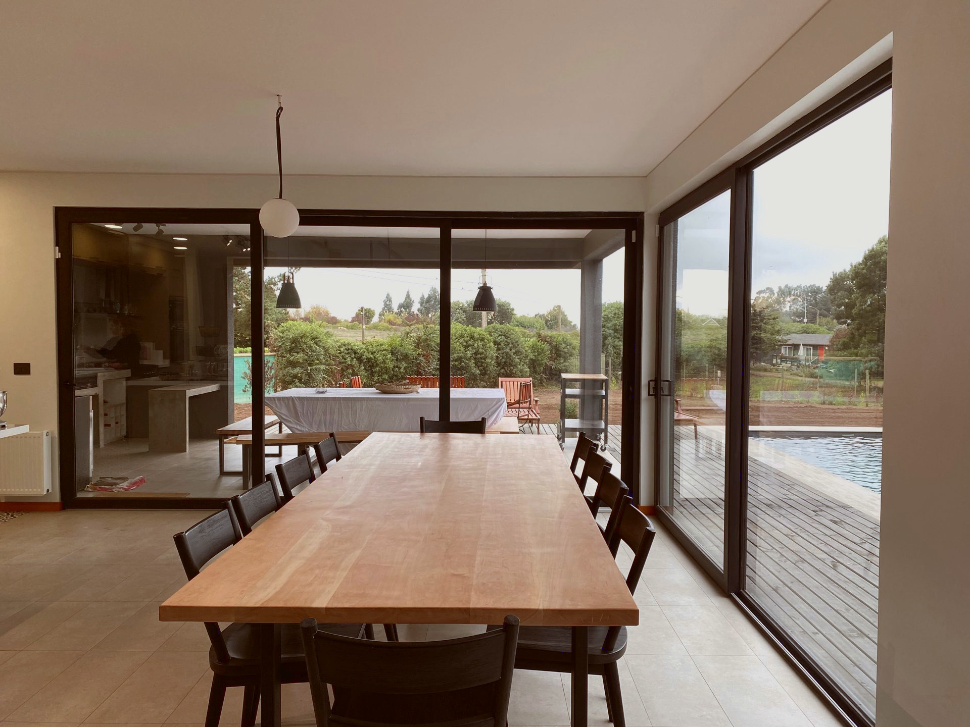 Puertas correderas grandes con perfiles de PVC antracita, en el comedor de una casa, con salida hacia la piscina.