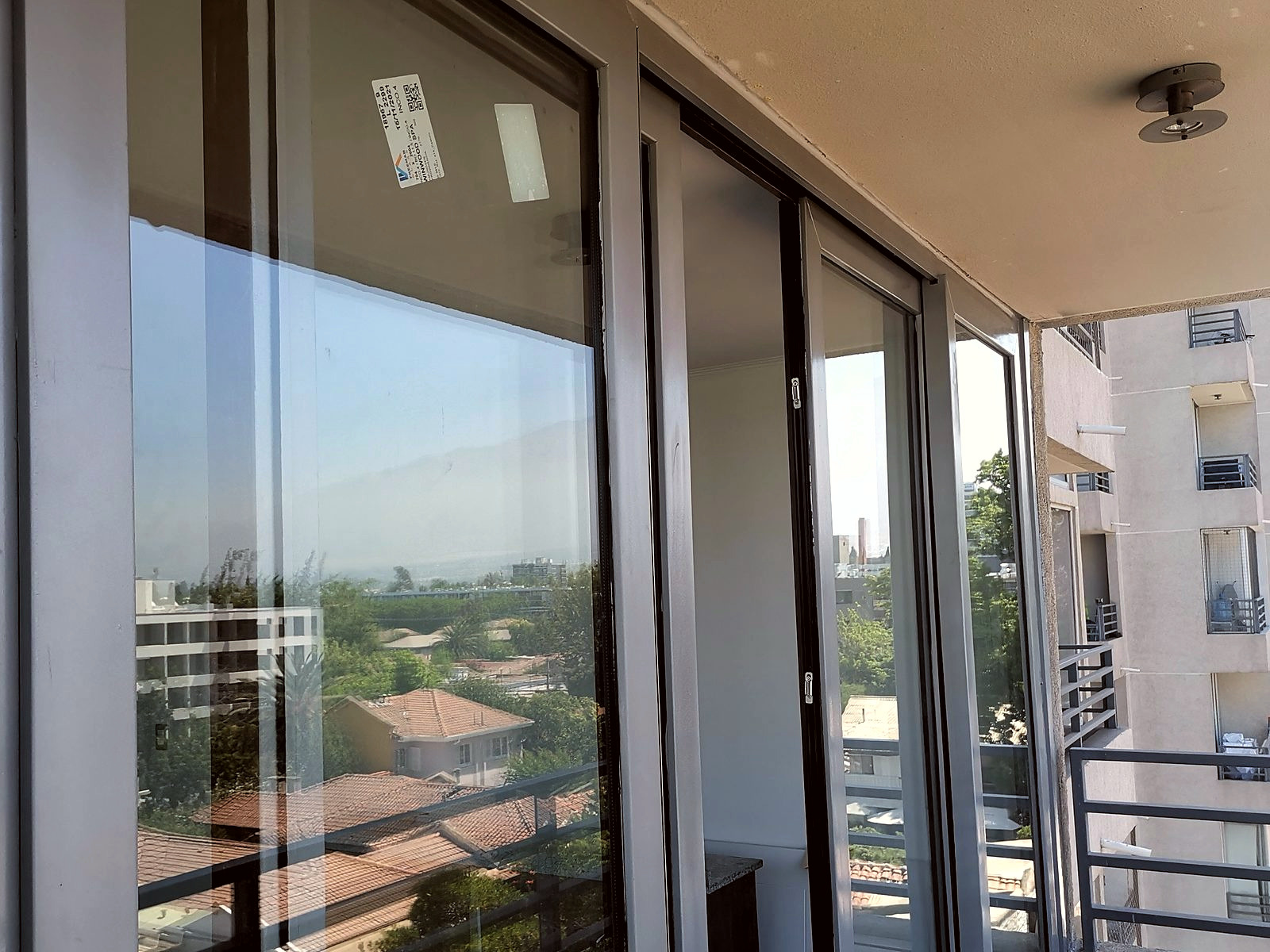 Ventanal corredero de PVC de piso a cielo, con perfiles gris claro, que da a la terraza de un departamento en altura.
